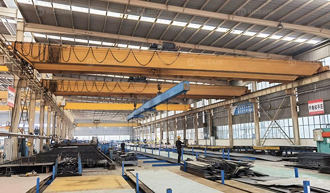 Multiple cranes operating simultaneously in a metal fabrication workshop