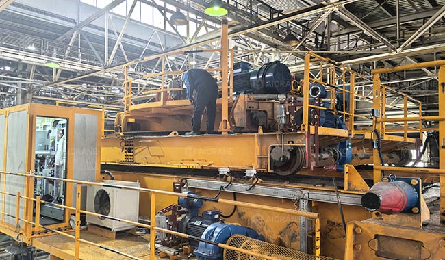 Technicians inspecting an overhead crane in a fabrication plant