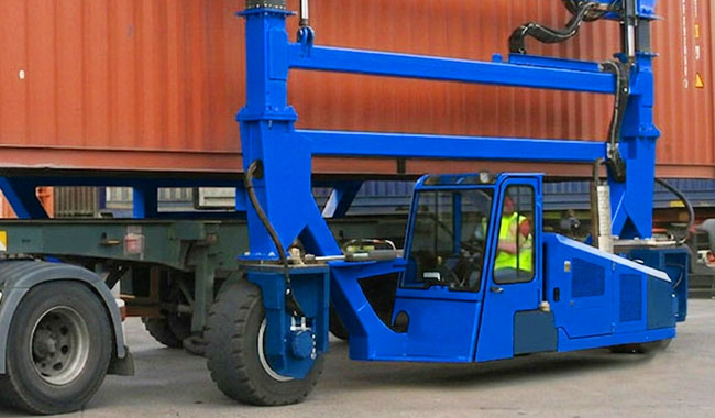 Straddle carrier operator controlling travel, steering, and lifting functions from the cabin