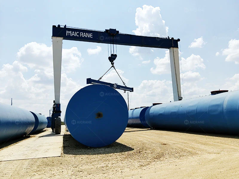 Rubber tyred gantry crane handling steel tanks in an industrial yard