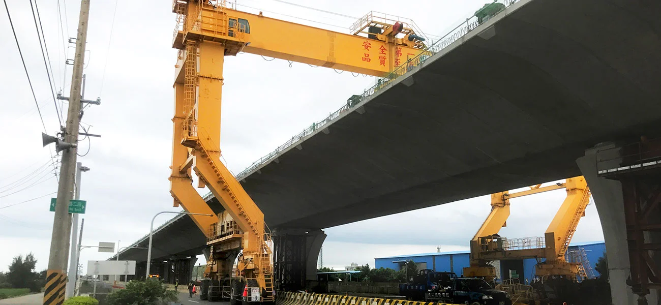 YTL hydraulic rubber tyred gantry crane transporting precast segments along a bridge construction site